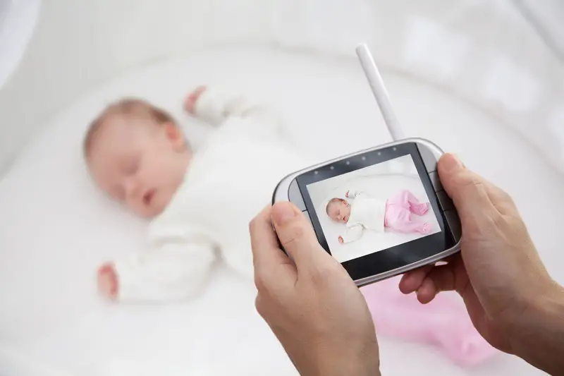 Mother Hand holding video baby monitor for security of the baby